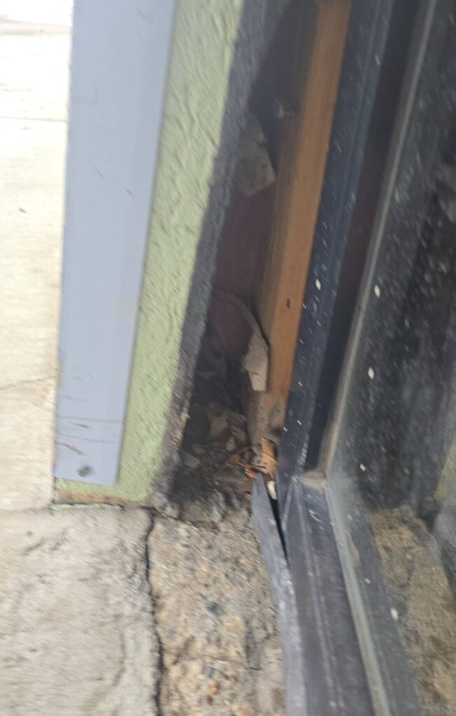 Storefront door jamb separated from the wall after a vehicle impact, documented before the rebuild.